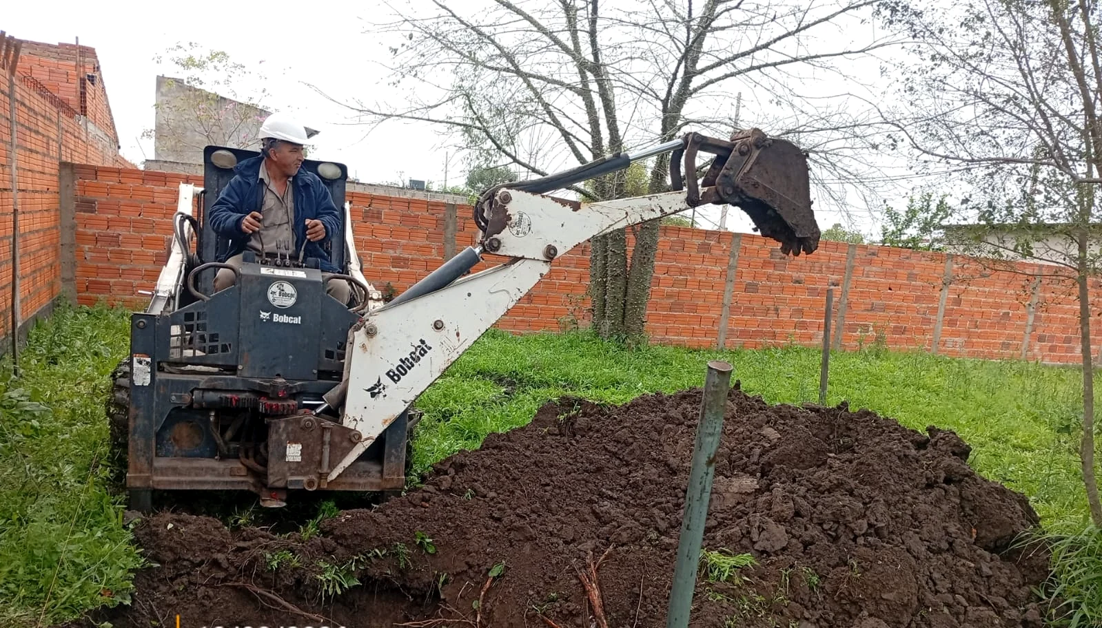 Minicargadora con brazo retroexcavador trabajando en el sitio